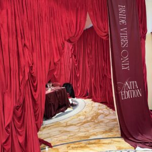 Red Drapes | Osmic Productions Luxurious Red Draped Curtains Framing a Wedding Reception Area with a Banner Reading Bride Vibes at Right.