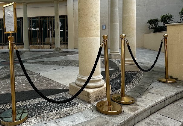 Screenshot 20260930 092552 | Osmic Productions Gold Stanchions with Black Rope Barrier Forming a Queue Outside a Columned Entrance.