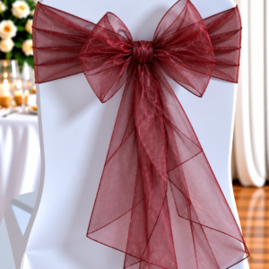 White chair with a burgundy organza bow tied around the back, part of event décor at a formal setting.