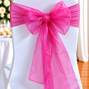 Organza Fuchsia Pink | Osmic Productions White Chair with a Bright Pink Sheer Sash Tied in a Large Bow at the Back, Decorative for a Wedding or Event Setup.