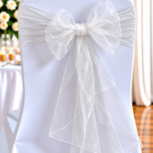 Organza Ivory | Osmic Productions White Chair with a Satin Cover and a Large Sheer White Bow Tied at the Back, Set for a Wedding Reception.
