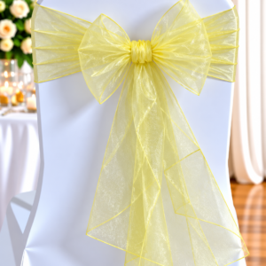 White Chair Dressed in White Fabric with a Pale Yellow Sheer Bow Tied at the Back, Suitable for a Wedding or Formal Event
