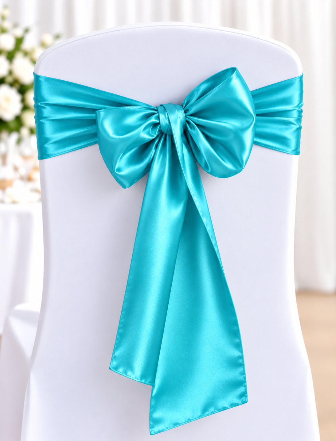 Satin Turquoise | Osmic Productions White Banquet Chair Covered in a White Fabric with a Turquoise Satin Ribbon Tied in a Large Bow at the Back, As Decor for a Formal Event.