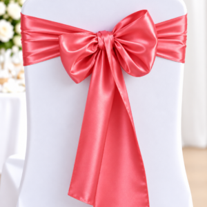 White chair covered in a white fabric with a pink satin ribbon tied in a large bow around the back, typical of wedding or event decor