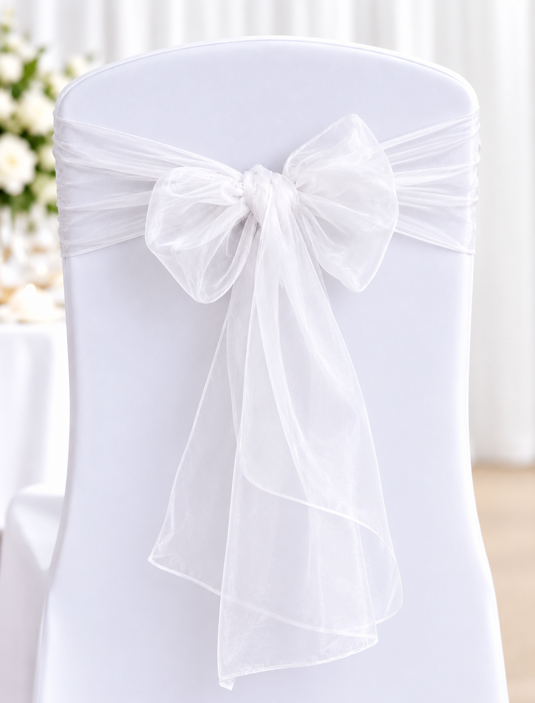 Sheer White | Osmic Productions White Chair Covered with a Sheer White Sash Tied in a Large Bow, Typical of a Wedding Decoration.